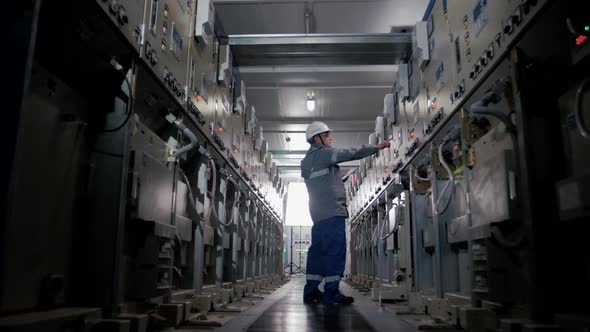 Power plant worker monitors the performance of devices in a high voltage switchboard