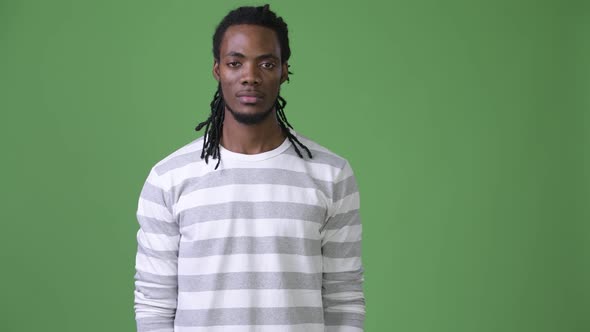 Young Handsome African Man with Dreadlocks Against Green Background