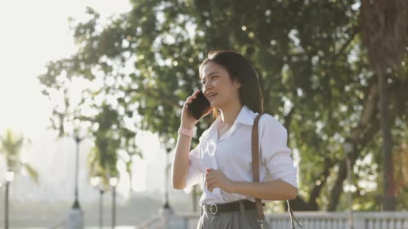 A beautiful Asian businesswoman in a white shirt is using a smartphone talking business.