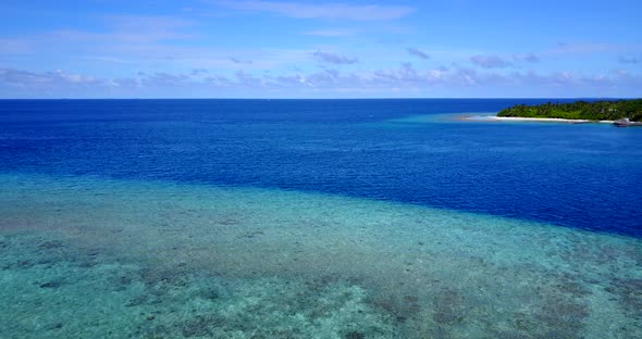 Wide angle flying copy space shot of a sandy white paradise beach and aqua blue water background in 