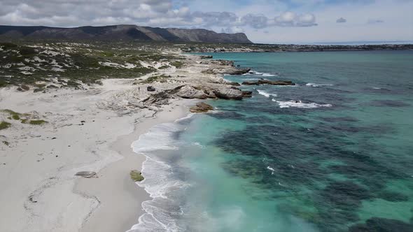 Coastal scene with blue ocean white sand dunes and mountains