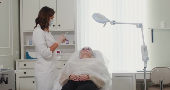 A Cosmetologist Makes an Injection of a Patient Face with Medical Preparations