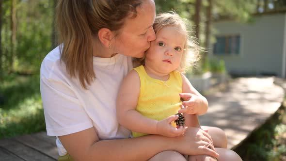 Little Cute Baby Toddler Girl Blonde with Curls on Mother's Arms