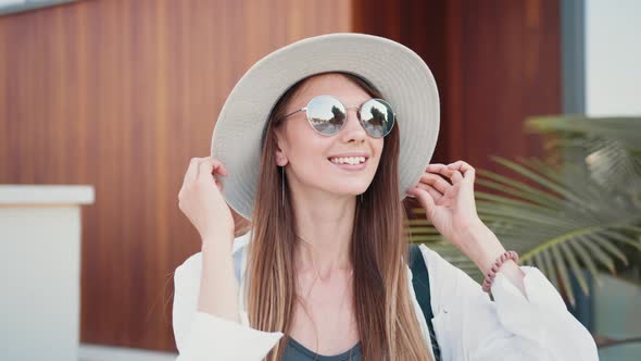 Adorable Woman in Sunglasses and Hat Posing on City Street