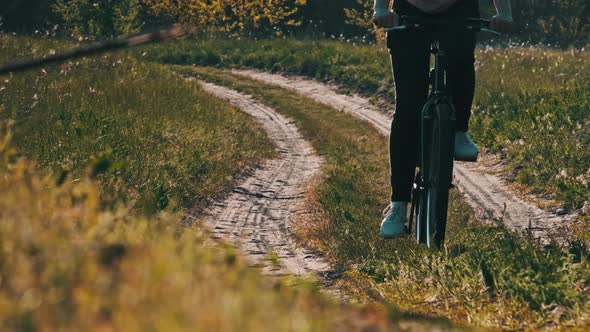 Young Woman on Bicycle Rides Along Green Forest Path in Summer Day Slow Motion