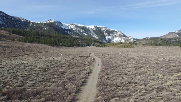 Aerial shot of young woman trail running in the mountains.