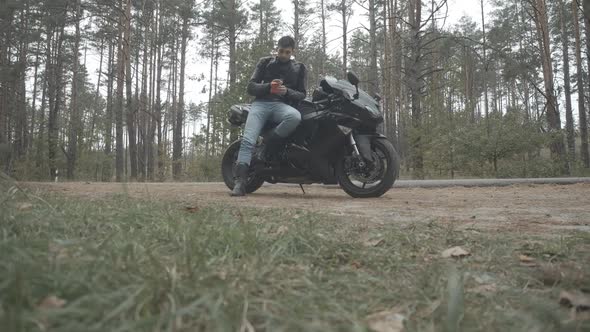 Wide Shot of Handsome Young Biker Looking at Engagement Ring and Thinking. Portrait of Confident