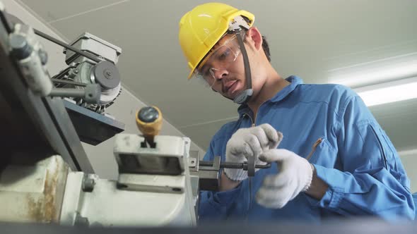 Asian mechanical technicians workers working on milling machine and operating the machine in factory