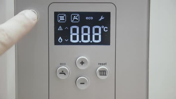 Male Finger Touches Boiler Display for Temperature Control