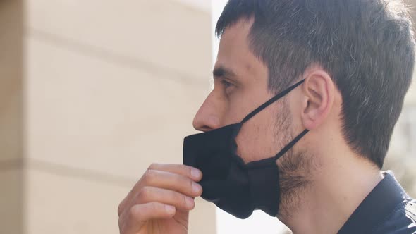 Man Takes Off a Protective Mask.