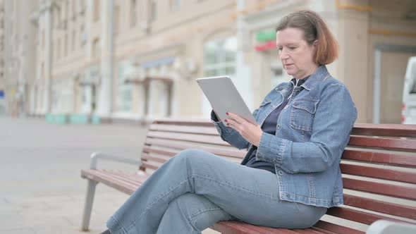 Old Woman Using Tablet While Sitting Outdoor on Bench