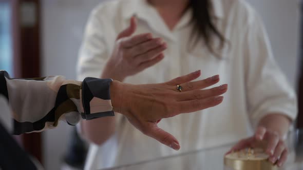 Closeup Female Hand with Ring with Gemstone and Unrecognizable Shop Assistant Gesturing at