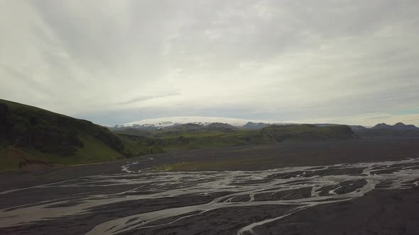 Aerial trucking of fiords, streams and verdant highlands, Breiðamerkurjökull glacier in background o