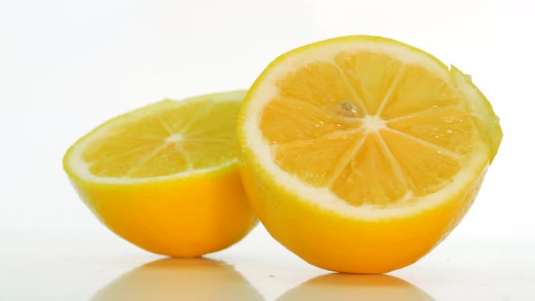 Natural Lemon On A White Background, The Lemon Is Spinning On The Table, Cut Into Two Slices