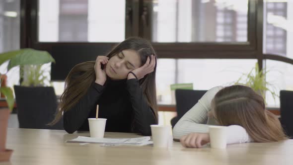 Attractive Girl Sitting at the Table Propped Head with Hand in the Office, Mixing Her Coffee