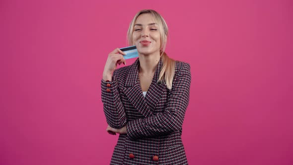 The Excited Young Woman with Her Bank Card in Her Hand Smiles Happily and Thinks of New Shopping