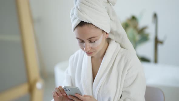 Caucasian Longhaired Woman Sitting on a Bath and Using Mobile Phone