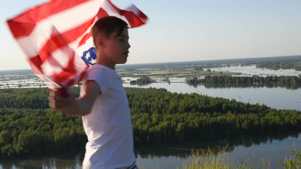 Blonde Boy Waving National USA Flag Outdoors Over Blue Sky at the River Bank