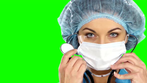 A Female Doctor with a Stethoscope Listening, Isolated on Green Screen