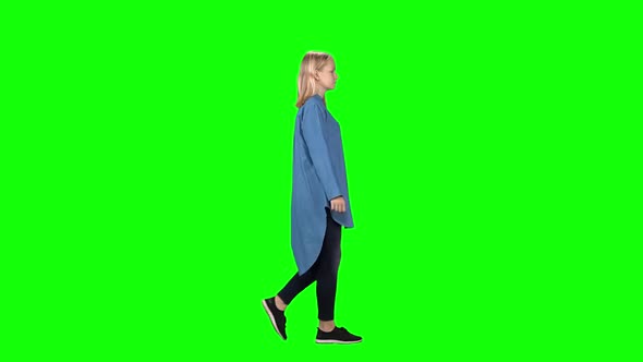 Blonde Teenager Girl Calmly Walking on Green Screen Background. Chroma Key. Profile View. Slow