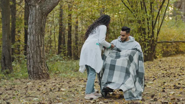 Young Nurse in Medical Gown Covers Guy with Warm Blanket Takes Care Patient in Wheelchair Caring