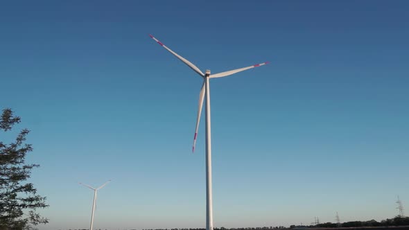 Working Two Huge Windmills in Summer in a Field at Sunset