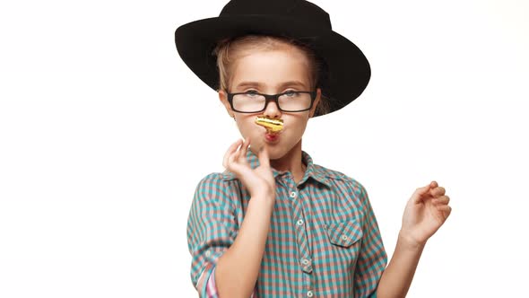 Small Beautiful Caucasian Kid Girl in Plaid Shirt Black Hat and Glasses Blowing Party Whistle on