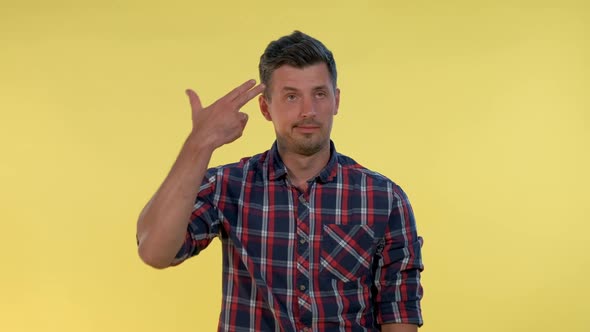 Portrait of Bored Young Man Shooting Herself in the Head with Finger Gun Gesture.