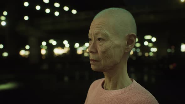 Old Asian Woman in City at Night