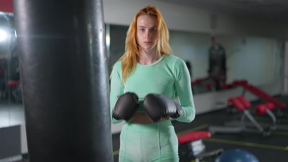 Medium Shot of Fit Strong Woman Hitting Boxing Gloves Posing in Gym Indoors