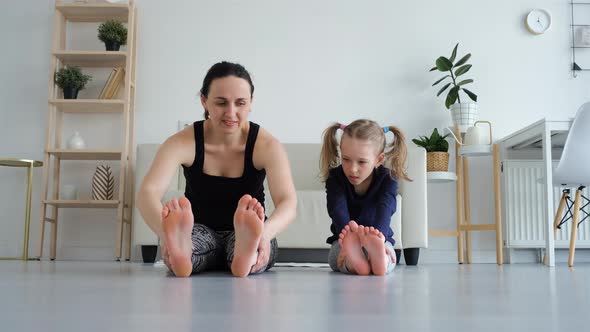 Little Girl with Mom Doing Stretching on a Floor