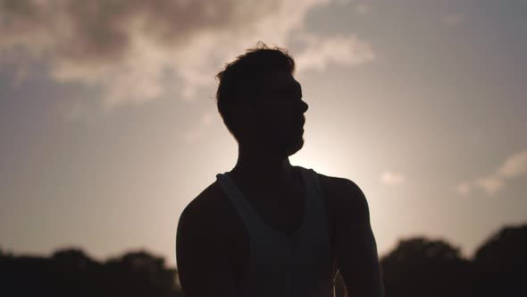 Man In Park Stretching Before Excercise Whilst Weing Silouetted By The Sun