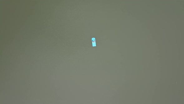 Aerial view of pedal boat with a family paddling on lake in summer. Dad, mom and a child 