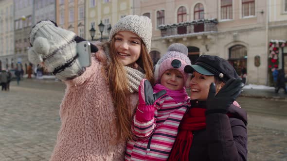 Women Tourists Taking Selfie Photos on Mobile Phone with Adoption Child Girl on Winter City Street