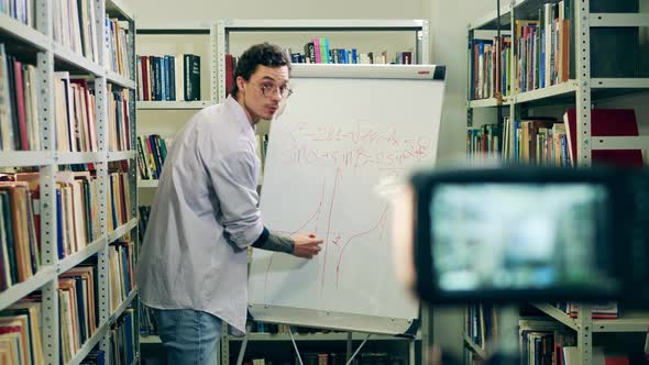 Male Teacher is Explaining Formulas During Online Lesson in a Library