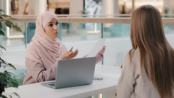 Two Young Girls Sitting at Table Friendly Muslim Woman Financial Advisor Explaining Benefits