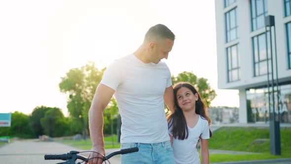 Dad and Daughter Walk Around Their Area After Cycling at Sunset