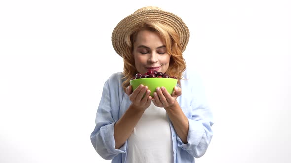 Positive Woman in Straw Hat Smelling Fresh Ripe Sweet Cherry Berry Selective Focus Seasonal Fruit