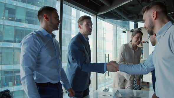 Young business negotiators shaking hands with partners after closing a deal in a modern office