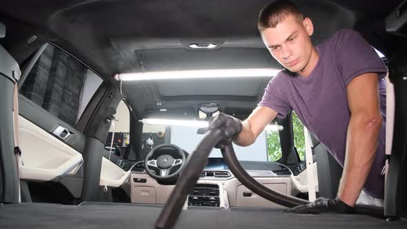 Male Worker Removing Dirt From Car Seat with Professional Vacuum Cleaner