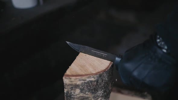 man cutting firewood with a knife in winter in Lemmenlaakso, Finland shot in120fps