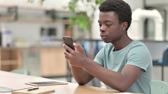 Young African Man Celebrating Success on Smartphone