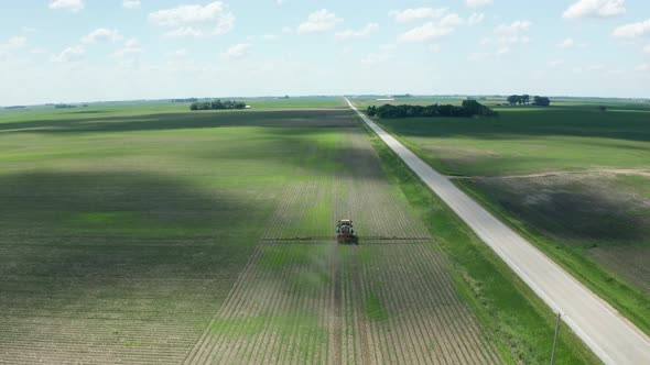 Aerial, tractor spraying pesticide on crops in rural agricultural farm field. Series