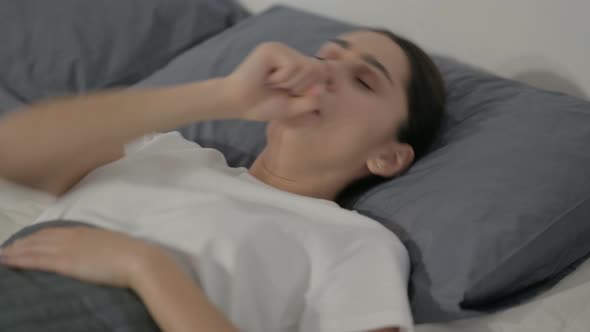 Hispanic Woman Coughing while Sleeping in Bed