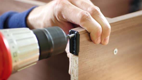 The Master Carpenter Screws the Screw with The Screwdriver. Man Collects Furniture. Men's Work