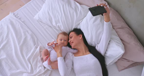 Beautiful Mother is Talking on a Video Call on a Smartphone Showing the Baby and Smiling