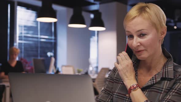 Mature Woman Using Laptop and Making Conversation on Smart Telep