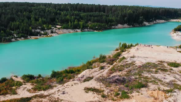 Landscape of a Light Blue Lake Surrounded By Sand - People Standing on a Mound of Sand