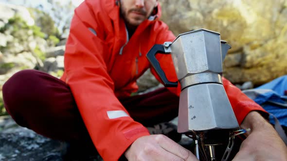 Male hiker preparing coffee in countryside 4k