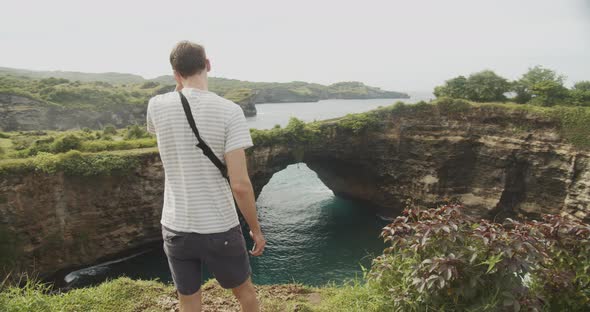 Close Up Medium Shot of a Male Tourist in Bali Looking at Stunning Arches and Cliffs of Broken Beach